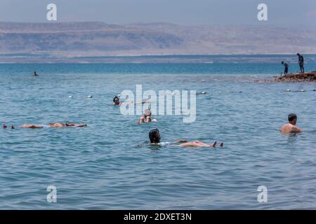 Turisti stranieri galleggiano sul Mar Morto in Giordania. Situato nella Jordan Rift Valley, l'acqua è 9.6 volte più salata dell'oceano. Foto Stock