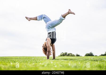 Atleta femminile che si esercita su erba in parco contro chiaro cielo Foto Stock