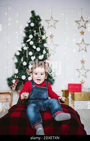 Allegro bambino ragazzo con bocca aperta giocando mentre si siede a. a casa durante il Natale Foto Stock