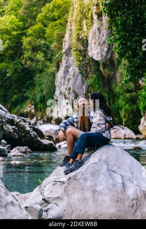 Felice giovane coppia seduta sulla roccia durante le escursioni in montagna Picos De Europa, Asturias, Spagna Foto Stock