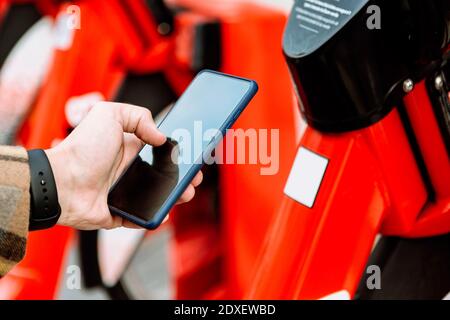 Mani che tengono smartphone per noleggiare una bicicletta Foto Stock