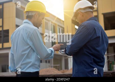 Due tecnici utilizzano la presentazione di notebook computer sul luogo di lavoro edificio edificio di background costruzione Foto Stock