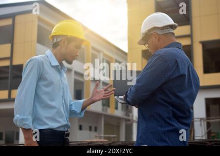 Due tecnici utilizzano la presentazione di notebook computer sul luogo di lavoro edificio edificio di background costruzione Foto Stock