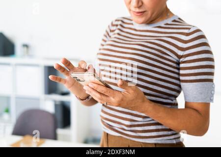 Metà della sezione della donna d'affari che usa lo smartphone Foto Stock