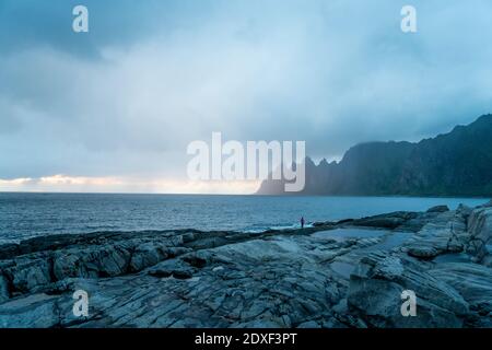 Escursionista che guarda la vista mentre si trova a Toggeneset, Senja, Norvegia Foto Stock