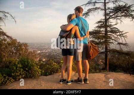La coppia si abbraccia guardando la vista in piedi sulla montagna Foto Stock