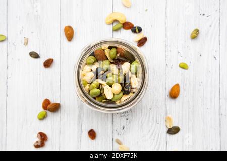 Vasetto di uvetta, arachidi, noci di anacardi, mandorle, soia, semi di girasole e semi di zucca su sfondo di legno Foto Stock