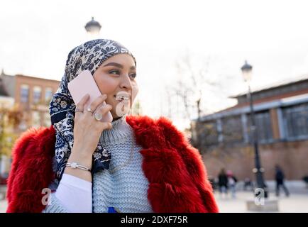 Bella donna con foulard e giacca in pelliccia che parla su cellulare telefono mentre si è in città Foto Stock