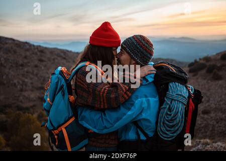 Coppia affettuosa in piedi faccia a faccia sulla montagna durante il tramonto Foto Stock