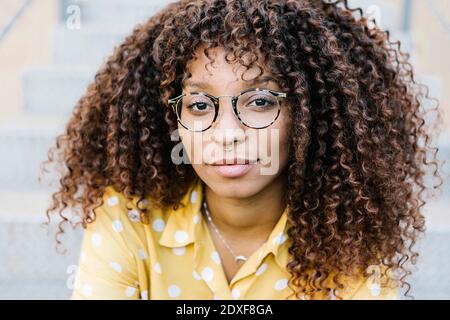 Giovane donna che indossa occhiali seduti all'aperto Foto Stock
