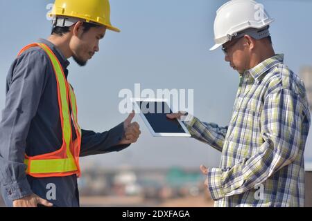 Due tecnici che utilizzano la tecnologia tablet per il controllo della costruzione dei lavori di ispezione e. gestione del progetto di pianificazione parlante Foto Stock