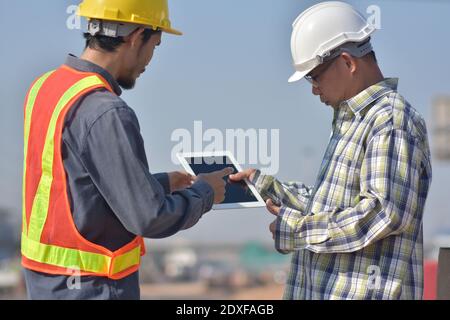 Due tecnici che utilizzano la tecnologia tablet per il controllo della costruzione dei lavori di ispezione e. gestione del progetto di pianificazione parlante Foto Stock