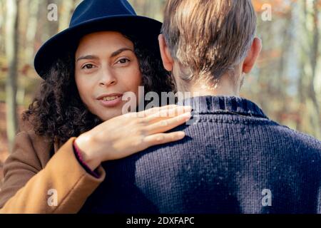 Donna che indossa il cappello che abbracciano l'uomo mentre si trova in piedi nella foresta Foto Stock