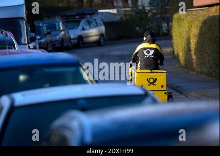 Amburgo, Germania. 21 Dic 2020. Un addetto alla consegna di Deutsche Post corre in bicicletta gialla lungo una strada residenziale. Credit: Jonas Walzberg/dpa/Alamy Live News Foto Stock