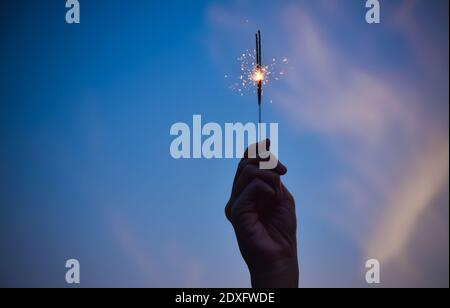 Mano che tiene fuochi d'artificio su Sky sera celebrazione Merry Natale e. Buona festa di nuovo anno Foto Stock