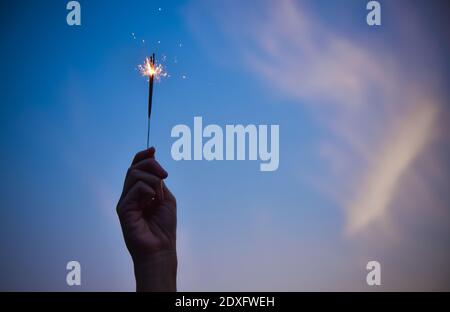 Mano che tiene fuochi d'artificio su Sky sera celebrazione Merry Natale e. Buona festa di nuovo anno Foto Stock