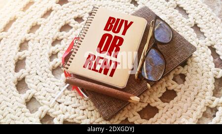 La domanda per comprare o affittare ha digitato su una copertina di libro, occhiali e penna. Analisi del mercato immobiliare e delle finanze personali. Concetto aziendale. Foto Stock