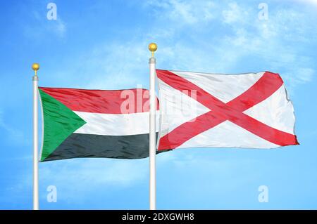 Sudan e Irlanda del Nord due bandiere su flagpoli e blu cielo Foto Stock