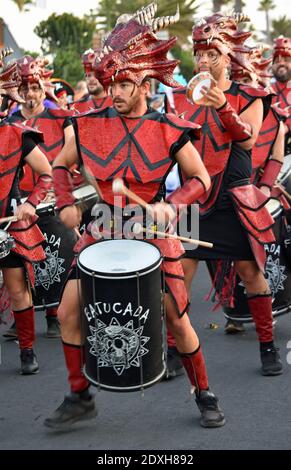 Batterista maschile carnevale in costume rosso che marciare e giocare. Foto Stock