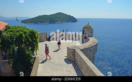 Mura della città di Dubrovnik con i turisti e l'isola di Lokrum in vista. Foto Stock