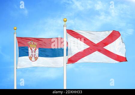 Serbia e Irlanda del Nord due bandiere su flagpoli e blu cielo Foto Stock