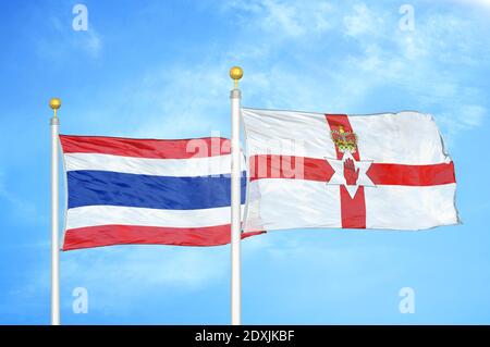 Thailandia e Irlanda del Nord due bandiere su flagpoli e blu cielo Foto Stock
