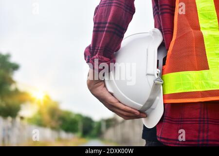 Primo piano tenuta mano bianco elmetto tecnico di sicurezza Contro lo sfondo del cielo Foto Stock