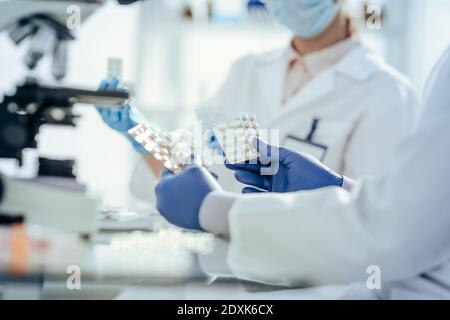 scienziati con campioni di nuovi farmaci seduti a un tavolo di laboratorio. Foto Stock