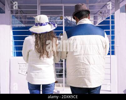 Una vista posteriore di una coppia che indossa cappotti bianchi e. cappelli Foto Stock