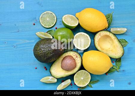 Piatto con cibo crudo. Avocado, lime, limoni e menta su sfondo blu. Copia testo spazio. Foto Stock