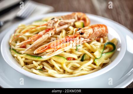 Tagliatelle fatte a mano con gamberi e zucchine in un piatto. Foto Stock