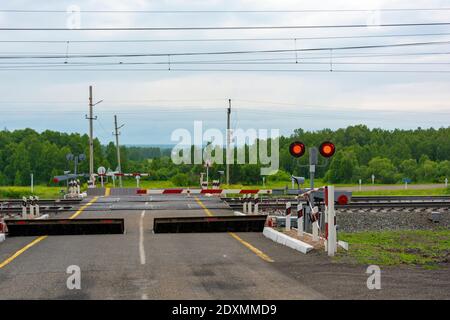 Attraversamento ferroviario della ferrovia TRANS-Siberiana, dotata di barriera automatica e barriere automatiche, regione Kemerovo-Kuzbass Foto Stock