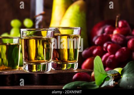 Rakija, raki o rakia - bevanda alcolica balcanica forte brandy tipo a base di frutta fermentata, tavola di legno d'annata, ancora vita in stile rustico, luogo f Foto Stock