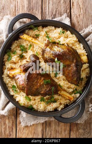 Haneeth deliziosa preparazione yemenita di agnello servito con la chiocchetta di riso nella padella sul tavolo. Vista dall'alto verticale Foto Stock