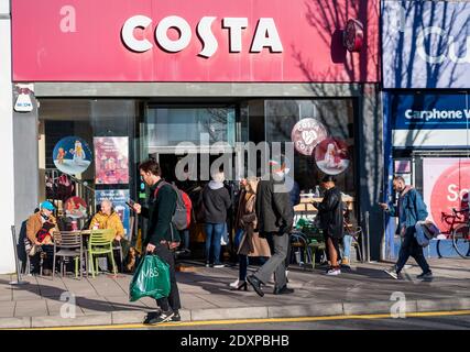 Brighton UK 24 dicembre 2020 - gli acquirenti della vigilia di Natale e alcuni che godono un caffè a Costa fuori a Brighton oggi prima che Sussex vada in coronavirus COVID-19 Tier 4 restrizioni sul giorno di Santo Stefano : Credit Simon Dack / Alamy Live News Foto Stock