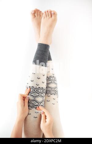 una donna mette sui leggings caldi grigi di lana, le gambe delle donne nelle leggings invernali Foto Stock