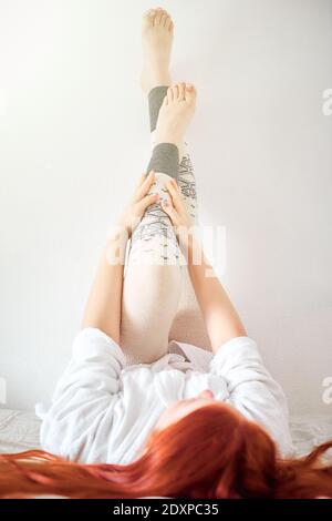 una donna mette sui leggings caldi grigi di lana, le gambe delle donne nelle leggings invernali Foto Stock
