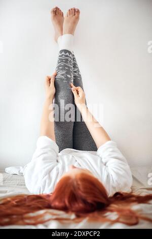 una donna mette sui leggings caldi grigi di lana, le gambe delle donne nelle leggings invernali Foto Stock