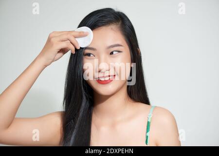 bella donna asiatica felice rimozione trucco dal viso con cotone elettrodi isolati su bianco Foto Stock