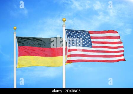Germania e Stati Uniti due bandiere su flagpoli e blu cielo nuvoloso Foto Stock