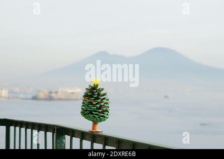 Albero di natale in miniatura - come decorazione fatta di cono di pino Sullo sfondo del Vesuvio Foto Stock