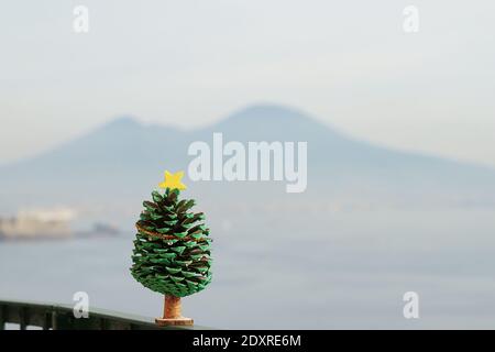 Albero di natale in miniatura - come decorazione fatta di cono di pino Sullo sfondo del Vesuvio Foto Stock