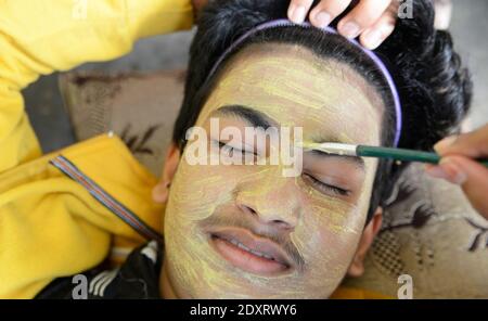 Ragazzo che si applica con maschera di fango di creta di pennello Foto Stock