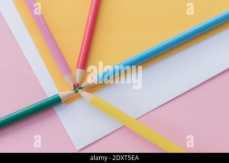 Pastelli multicolore su fogli di carta (giallo, bianco e rosa) Foto Stock