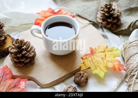 Foglie autunnali, tazza di caffè calda e fumante su sfondo bianco. Concetto di relax e di vita still. Foto Stock