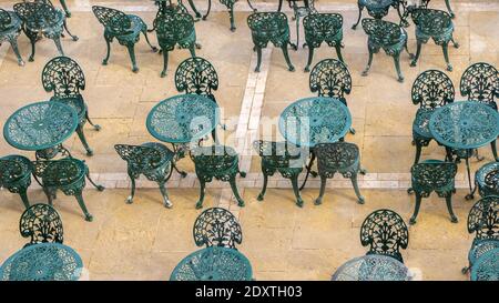 Vista dall'alto della caffetteria all'aperto sulla terrazza estiva con tavoli e sedie in metallo verniciato di verde per i visitatori che non hanno nessuno su di loro. Sedie da caffè vintage e. Foto Stock