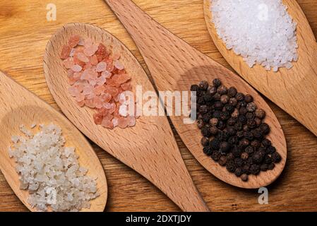 Quattro cucchiai di legno con grani di pepe nero, Kosher e cristalli di sale marino Foto Stock