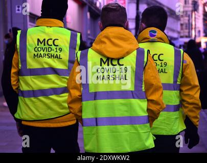 Covid Marshalls, dipendente dall'autorità locale, Manchester City Council, pattuglia il centro della città di Manchester, Greater Manchester, Inghilterra, Regno Unito la vigilia di Natale, 2020. Foto Stock