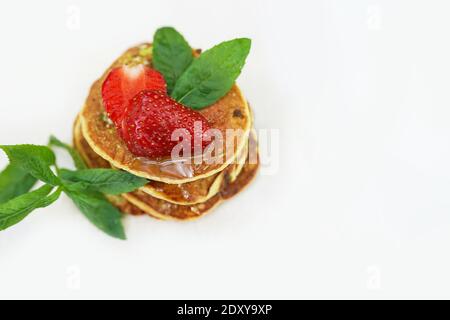 frittelle dorate soffici con fragole e sciroppo su sfondo bianco con spazio per la copia Foto Stock