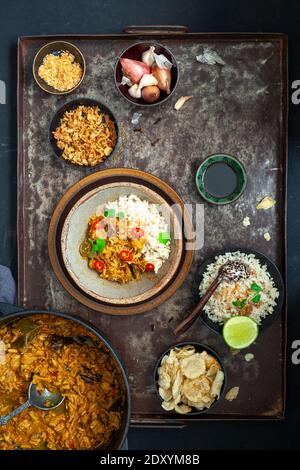 Una vista ad alto angolo del jackfruit indonesiano vegano fatto in casa rendang servito con riso su un piatto marrone e accompagnamenti Foto Stock